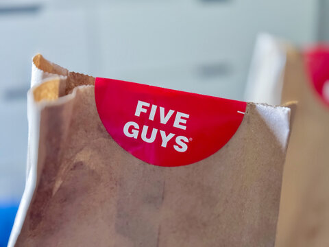 Calgary, Alberta, Canada. May 21, 2024. A Five Guys Food chain restaurant sticker on a paper back.