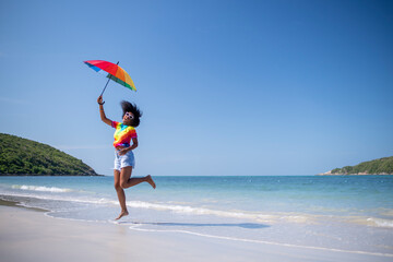 Happiness woman smiles and jumping relaxed summer holiday on ,rainbow t-shirt and rainbow umbrella...