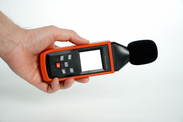 hand holding a digital sound level on a white background,Sound level meters are commonly used in noise pollution studies.