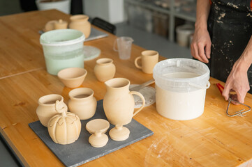 Close-up of a potter's hands glazing a ceramic mug. 