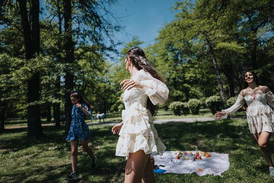 Three young women frolicking outdoors in a lush park, embodying freedom and joy on a bright sunny day.