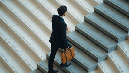 Top view of smart business man walking up stairs with bag in the hand. Professional project manager climb up the stair and going to workplace. Increasing skill, getting promotion, traveling. Exultant.