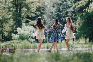 Three young females, possibly sisters, share a joyful moment dancing carefree in a lush green park...