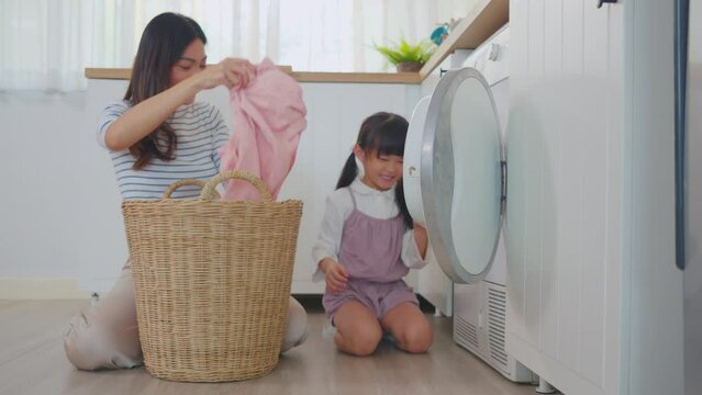 Asian beautiful mother teach young daughter wash dirty clothes at home. 