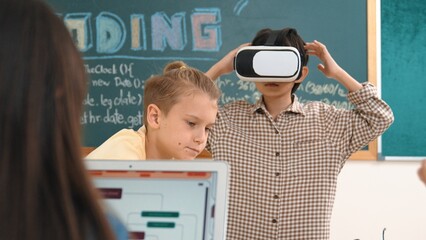 Energetic child wearing Vr headset while enter virtual world at classroom. Student programing...