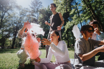 A group of young friends relax and enjoy cotton candy on a sunny day in a lush green park,...