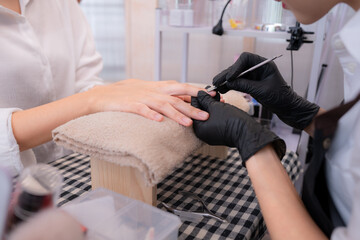 A nail technician is using tools to cut and polish nails of a customer.