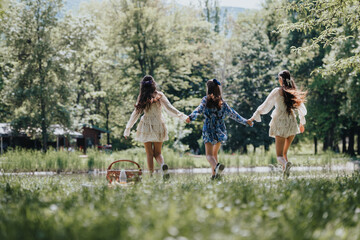 Three young girls holding hands and running care freely through a lush green park, embodying the...