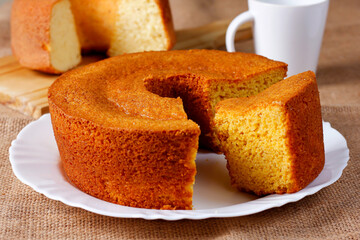Homemade corn cake on white plate on rustic wooden table. Typical Brazilian party food.