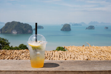 A plastic glass of cold lemon soda sits on the balcony with the sea as a background.