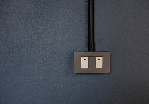 Black box light switch on the wall painted dark blue.