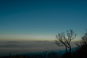 A photo of a view of mountains with clouds and clear blue sky seen from the top of Mount Ciremai, West Java, Indonesia