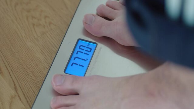 Closeup shot of man stepping on a weight scale