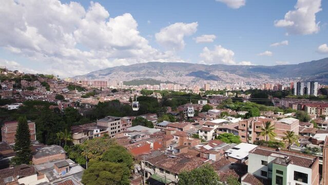 Metrocable ropeway over urban slum district in Medellin Town, Colombia. Tourist attraction in dangerous district. Aerial wide shot.