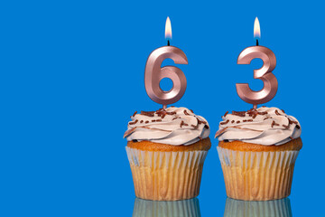 Birthday Cupcakes With Candles Lit Forming The Number 63.