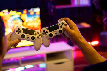 Close up of hands couple or friends joyful player video game on TV using to bring joysticks...