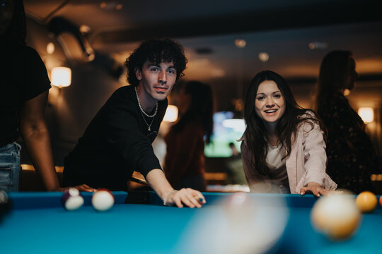 A group of friends gathers for a happy and fun night out, playing billiards together at a local bar.
