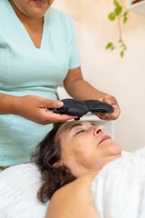 Masseur applying heated eye mask to woman in a spa