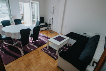 A well-lit interior of a modern apartment showcasing a living space with comfortable sofa and dining area.