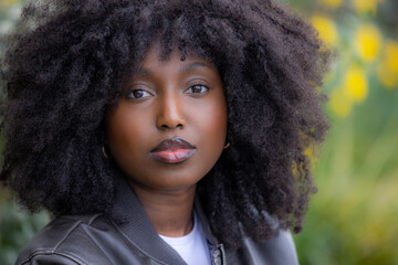 This image features a close-up portrait of a Black woman with natural, curly hair, captured...