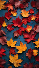 A collection of vibrant autumn leaves in shades of red, orange, and yellow scattered on a dark blue surface.