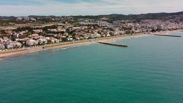 Sitges, spain, showing the coastline and cityscape with mountains in the background, aerial view