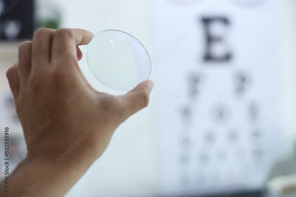 Sticker close up of a hand holding a magnifying glass, hand holding glasses lens in optical store