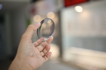 close up of a person holding a magnifying glass, hand holding glasses lens in optical store 