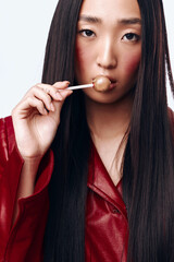 Obraz premium Young woman with long black hair and a red jacket brushing her teeth with a toothbrush