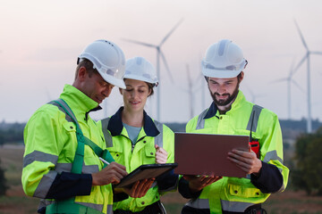 Team engineer wearing safety uniform holding laptop discussed plan about renewable energy at station energy power wind. technology protect environment reduce global warming problems.