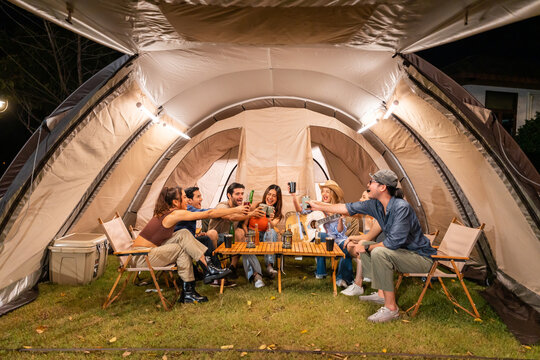 Group of diverse friend having outdoors camping party together in tent.