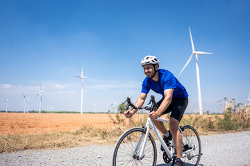Caucasian active sportsman riding bicycle at the wind turbine field. 