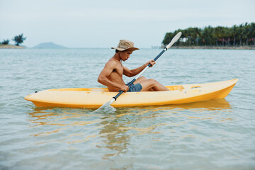 Happy Asian Man Kayaking on a Tropical Beach: Adventure and Enjoyment in Nature
