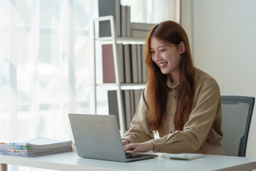 Asian businesswoman sits and works with laptop in contacting customers online. View details and discuss financial business information. Happiness in wealth Success in the office.