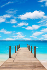 Wooden dock extending into the ocean with blue sky and clouds.