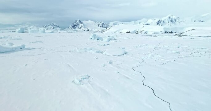 Towering mountains desert snow covered Antarctic landscape. Aerial drone fly over frozen ocean coast, ice floe crack. Beautiful South Pole winter wild nature footage. Antarctica travel and exploration