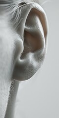 Close-up of a human ear against a neutral background, showcasing intricate details and texture of the ear anatomy.