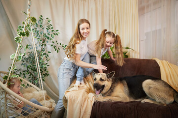 Loving family with mother, daughter and big dog in living room. Woman mom or babysitter and female...
