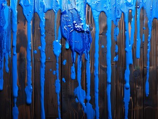 Abstract image of blue paint dripping on a dark wooden surface, creating a vibrant and textured artistic background.