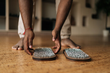 Closeup cropped shot of unrecognizable barefoot black male getting ready to get up on wooden Sadhu...