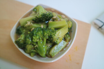 Stir fried broccoli or ca broccoli with thick sauce made from cornstarch. with garlic pieces on it. Indonesian food, served in a bowl.