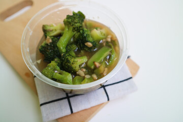 Stir fried broccoli or ca broccoli with thick sauce made from cornstarch. with garlic pieces on it. Indonesian food, served in a bowl.
