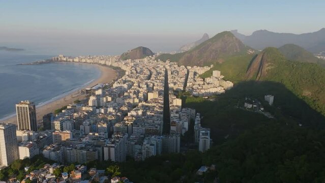 Wide aerial footage in Rio de Janeiro during the sunrise of Copacabana that's it beach with R. Barata Ribeiro centered in the frame.