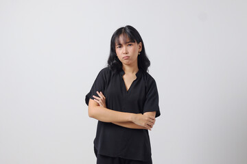 Portrait of unpleasant Asian woman in casual shirt keeping arms crossed and looking at camera with skeptical and distrustful look. Isolated image on white background