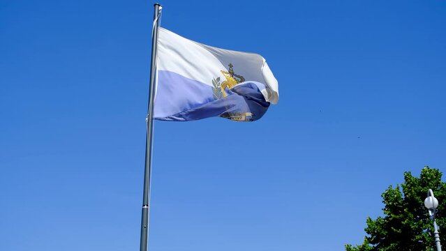 Flag of the Republic of San Marino in moderate wind at government building.
