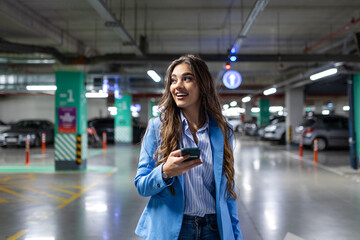 A woman stands in a parking lot, texting on her smart mobile phone