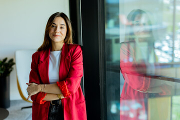 Confident young professional in red blazer smiling at modern office environment