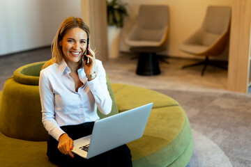 Businesswoman working on laptop while on a call in a modern office