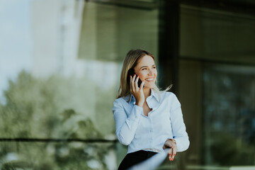 Young professional woman talking on a phone call outdoors on a sunny day