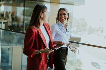 Two businesswomen discuss strategy outside modern office building in daylight